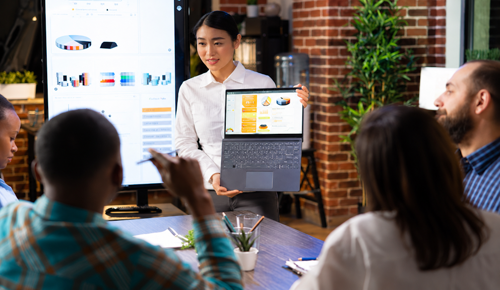 Marketing team in Jakarta reviewing campaign results on a laptop and screen while planning a product launch with an event organizer and 24-hour printing for banners and brochures
